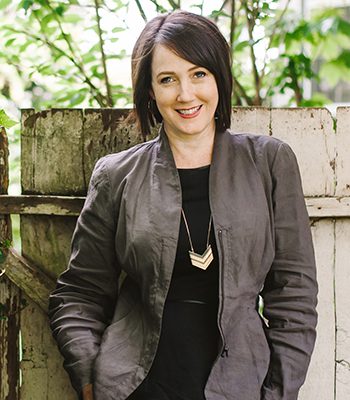 A woman standing next to a wooden fence.