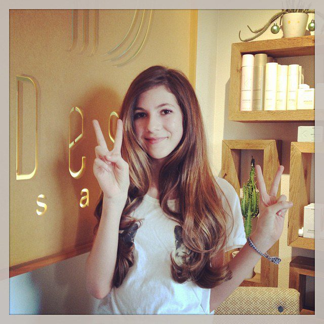 A girl with long hair is giving the peace sign.