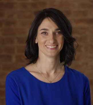 A woman in blue shirt smiling for the camera.