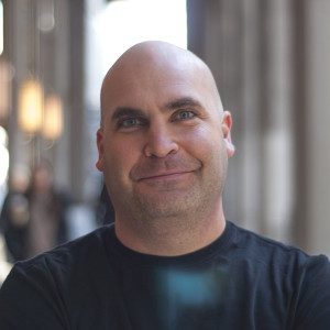 A bald man with a shaved head smiling for the camera.